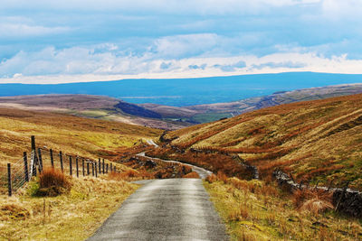 Road leading towards mountains against sky