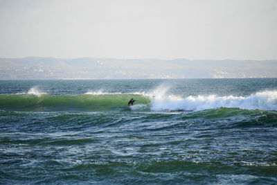 Man surfing in sea against sky