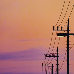 Low angle view of silhouette electricity pylon against sky during sunset