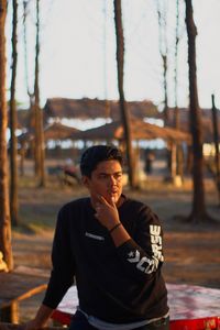 Portrait of young man standing against tree