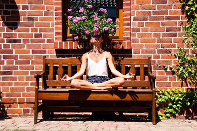 Woman sitting on bench against the wall