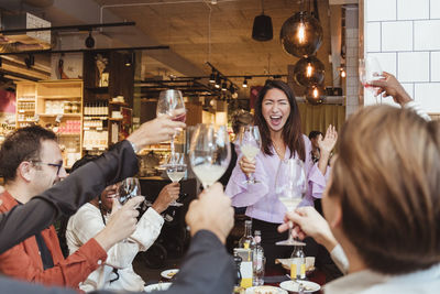 Cheerful male and female friends toasting wineglasses at restaurant