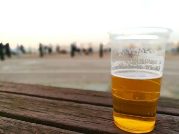 Close-up of beer glass on table against sky