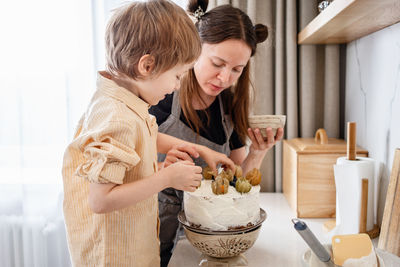 Mother and son baking carrot cake together at cozy kitchen. home cooking, family life