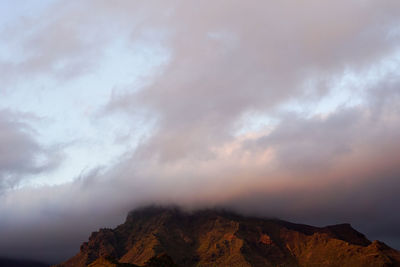 High section of mountain range against clouds