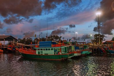 Boats in river against cloudy sky