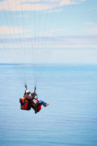 Low angle view of person paragliding against sky