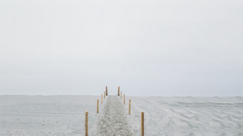 Wooden posts on beach against clear sky