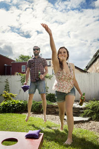 Happy couple playing bean bag toss game in lawn