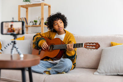 Young woman using laptop while sitting on sofa at home