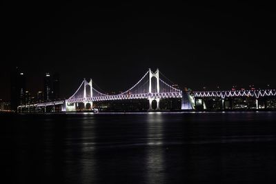 Illuminated suspension bridge against sky at night