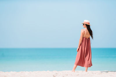 Woman standing at beach against sky