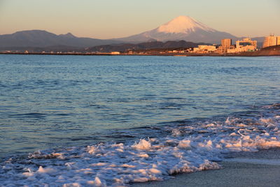 Scenic view of sea and snowcapped mountain against sky