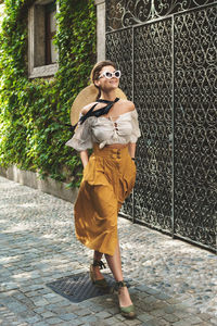 Full length of young woman standing against wall
