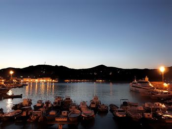 Boats moored in sea against clear sky at dusk