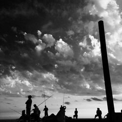 Silhouette of people against cloudy sky