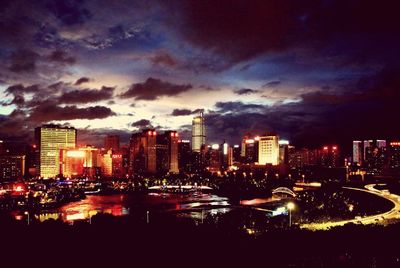 Illuminated cityscape against cloudy sky