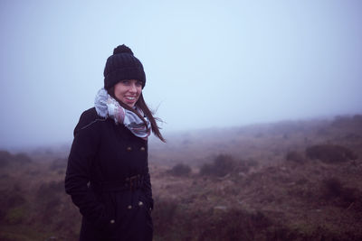 Portrait of young woman standing on land against sky