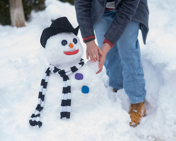 Low section of man standing on snow covered field