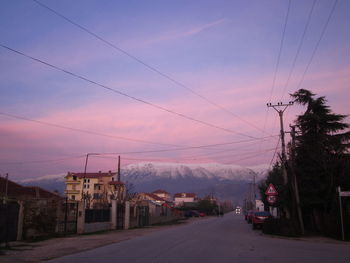 Road by city against sky during sunset