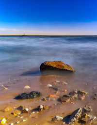 Scenic view of rocks on beach against sky