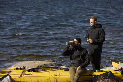 Men near kayaks on rocky coast