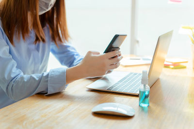 Midsection of woman using laptop on table