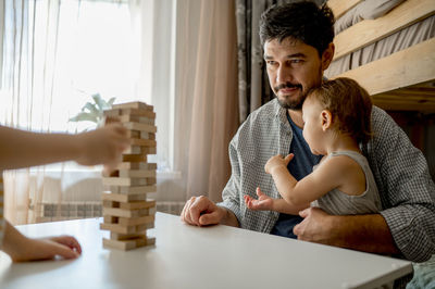 Father with son looking at block removal game on table at home