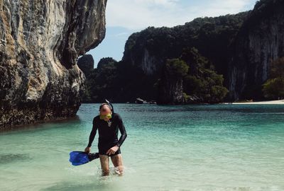 Man walking in sea against mountains