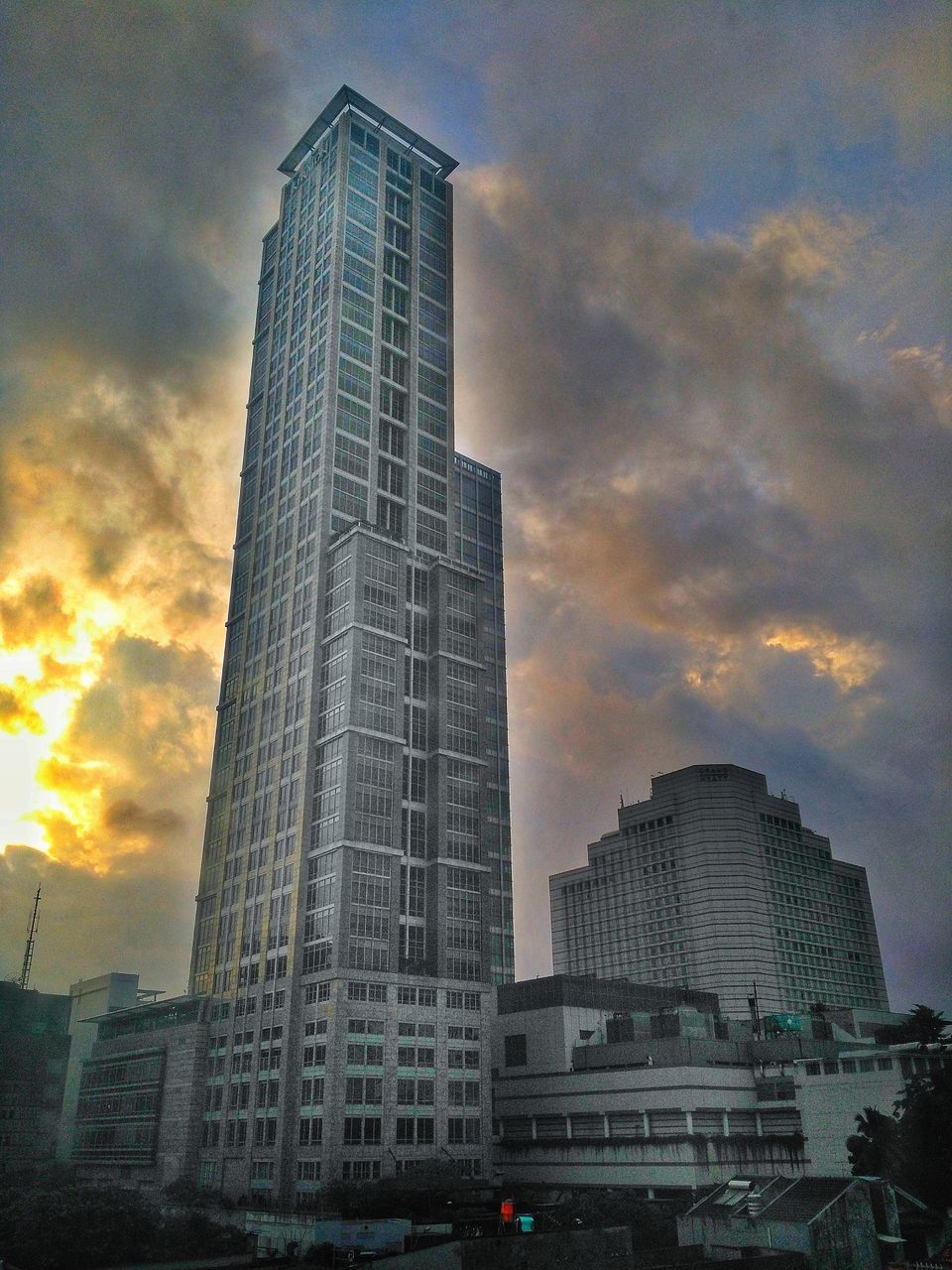 skyscraper, architecture, building exterior, built structure, city, tall - high, modern, sky, low angle view, tower, tall, downtown district, cloud - sky, city life, development, cityscape, outdoors, sunset, no people, urban skyline, growth, storm cloud, day