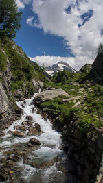 Scenic view of waterfall and mountains against sky