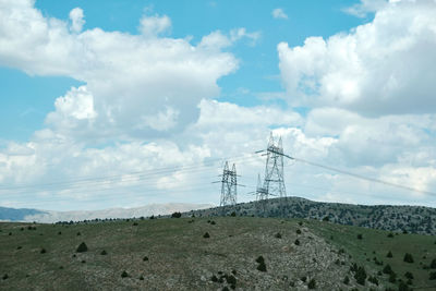 Electricity pylon on land against sky