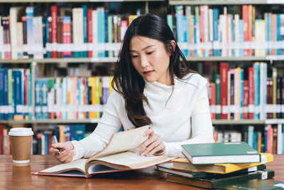 Young woman sitting on book at table