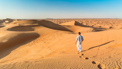 Rear view of man walking at desert