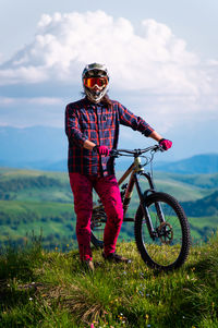 Unrecognizable athlete in protective gear standing in a field and looking at the camera against the