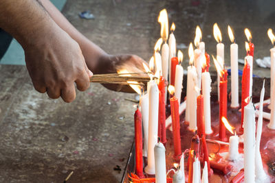 Cropped hands of people igniting candle in church