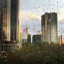 Buildings seen through wet glass window during rainy season