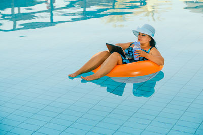 High angle view of woman using laptop while sitting on inflatable ring