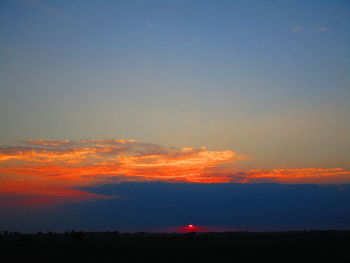 Scenic view of silhouette field against sky at sunset