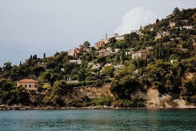 Scenic view of sea by buildings in town against sky