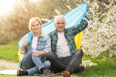 Portrait of smiling friends sitting on field