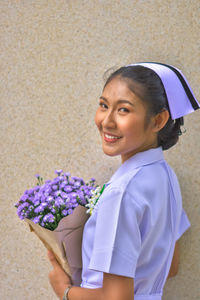 Portrait of a smiling young woman holding purple flower