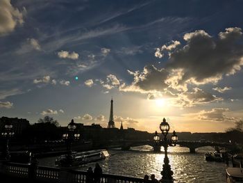 Silhouette bridge over river against sky during sunset