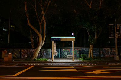 Illuminated bus shelter at sidewalk in city