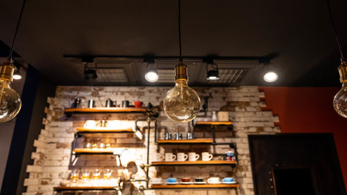 Low angle view of illuminated pendant light hanging from ceiling in restaurant