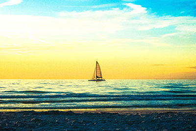 Silhouette sailboat sailing on sea against sky at sunset