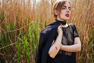 Portrait of young woman standing against plants