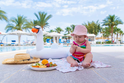 Girl holding fruit sitting by inflatable ring