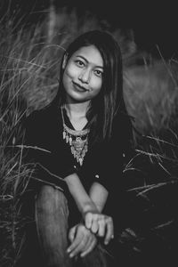 Young woman sitting amidst grass on field