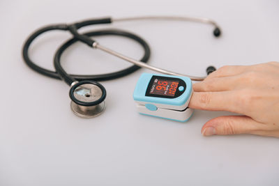 Cropped hand of doctor holding stethoscope against white background